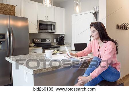 Caucasian woman reading paperwork in kitchen View Large Photo Image Stock Image - Caucasian woman reading paperwork in kitchen. Fotosearch