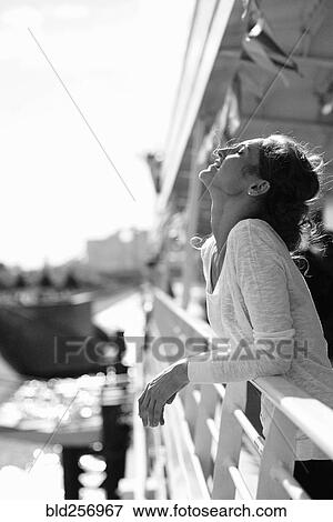 Stock Photo - Caucasian woman relaxing and leaning on railing. Fotosearch