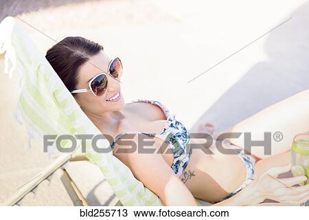 Caucasian woman relaxing in lounge chair holding drink View Large Photo Image Stock Image - Caucasian woman relaxing in lounge chair holding drink. Fotosearch