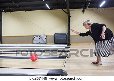 Stock Photo - Caucasian woman releasing bowling ball in lane. Fotosearch