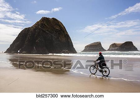 Stock Image - Caucasian woman riding bicycle on beach. Fotosearch