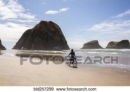 Stock Photo - Caucasian woman riding bicycle on beach. Fotosearch