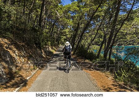 Stock Photo - Caucasian woman riding bicycle on path near lake. Fotosearch