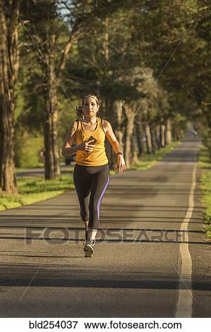 Caucasian woman running on path listening to cell phone View Large Photo Image Stock Photo - Caucasian woman running on path listening to cell phone. Fotosearch