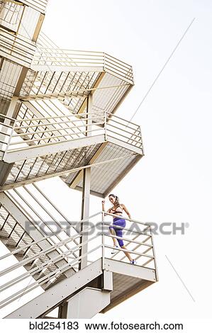 Stock Image - Caucasian woman running on urban staircase. Fotosearch