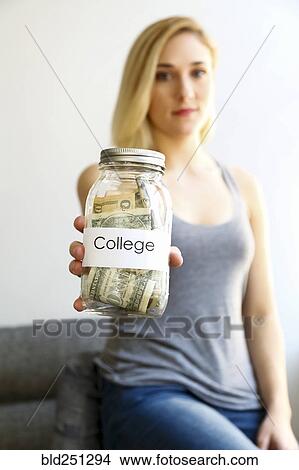 Picture - Caucasian woman showing jar of money for college. Fotosearch
