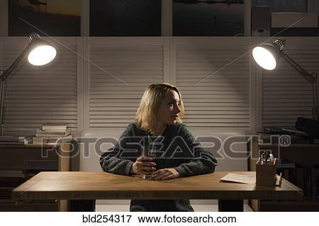 Stock Photo - Caucasian woman sitting at desk drinking beverage. Fotosearch