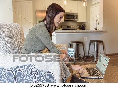 Caucasian woman sitting in armchair using laptop and drinking coffee View Large Photo Image Stock Image - Caucasian woman sitting in armchair using laptop and drinking coffee. Fotosearch