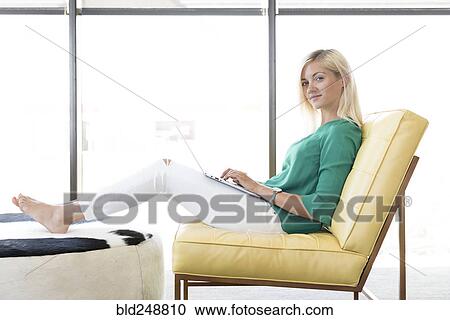 Caucasian woman sitting in chair using laptop View Large Photo Image Stock Image - Caucasian woman sitting in chair using laptop. Fotosearch