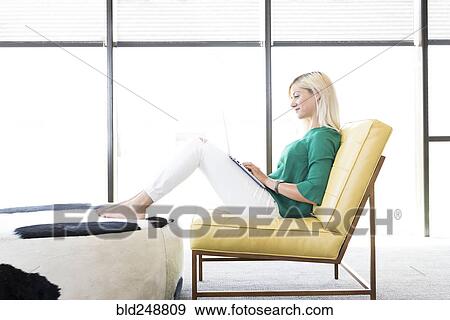 Caucasian woman sitting in chair using laptop View Large Photo Image Stock Photo - Caucasian woman sitting in chair using laptop. Fotosearch