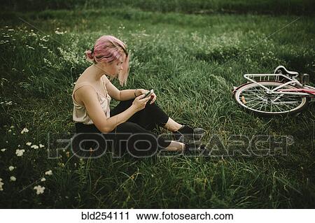Caucasian woman sitting infield texting on cell phone View Large Photo Image Stock Image - Caucasian woman sitting infield texting on cell phone. Fotosearch