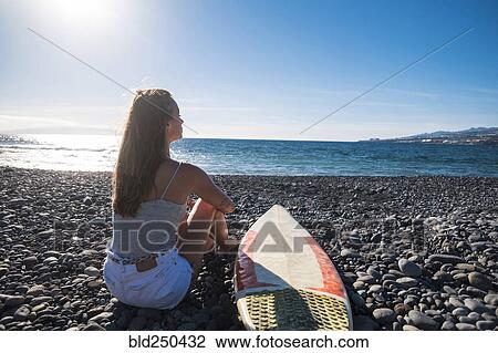 Caucasian woman sitting on beach near surfboard View Large Photo Image Stock Image - Caucasian woman sitting on beach near surfboard. Fotosearch