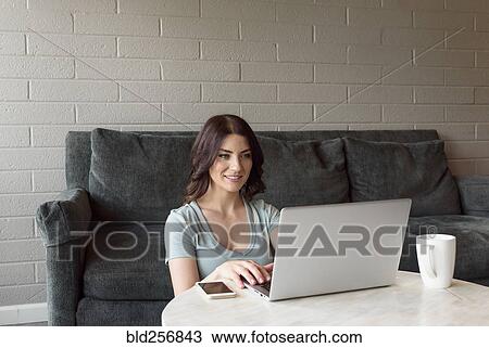 Caucasian woman sitting on floor near sofa using laptop View Large Photo Image Stock Image - Caucasian woman sitting on floor near sofa using laptop. Fotosearch