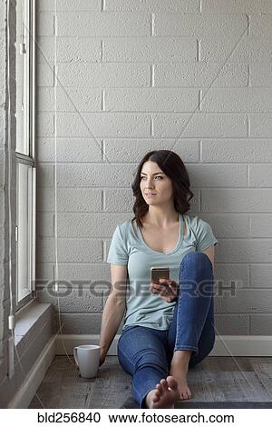 Caucasian woman sitting on floor texting on cell phone View Large Photo Image Stock Image - Caucasian woman sitting on floor texting on cell phone. Fotosearch