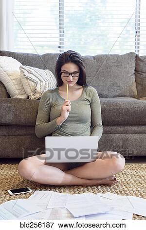 Caucasian woman sitting on floor using laptop near paperwork View Large Photo Image Stock Photo - Caucasian woman sitting on floor using laptop near paperwork. Fotosearch