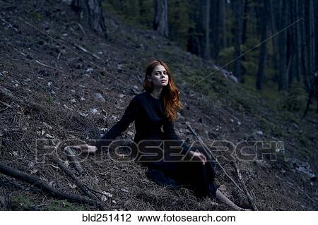 Stock Image - Caucasian woman sitting on hill. Fotosearch
