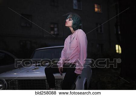 Caucasian woman sitting on hood of car at night View Large Photo Image Stock Photo - Caucasian woman sitting on hood of car at night. Fotosearch