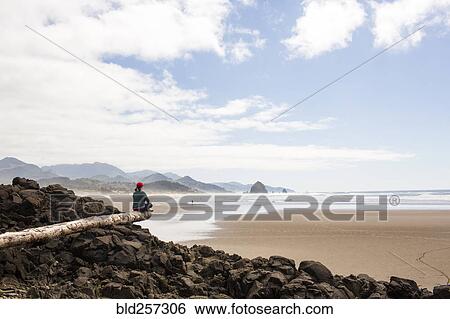 Caucasian woman sitting on log on rocks at beach View Large Photo Image Stock Photograph - Caucasian woman sitting on log on rocks at beach. Fotosearch