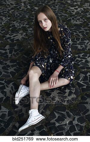 Stock Photo - Caucasian woman sitting on stone floor. Fotosearch