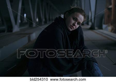 Stock Image - Caucasian woman sitting under bridge. Fotosearch
