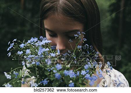 Stock Image - Caucasian woman smelling flowers. Fotosearch