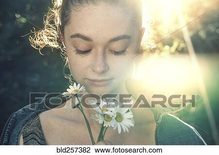 Stock Image - Caucasian woman smelling flowers. Fotosearch
