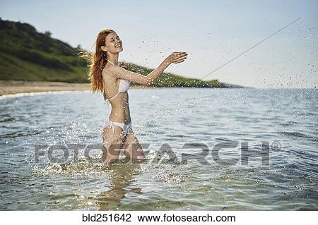 Stock Image - Caucasian woman splashing in ocean. Fotosearch