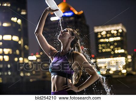 Caucasian woman spraying water on face in city at night View Large Photo Image Stock Image - Caucasian woman spraying water on face in city at night. Fotosearch