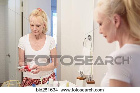 Caucasian woman squeezing lotion onto finger in mirror View Large Photo Image Picture - Caucasian woman squeezing lotion onto finger in mirror. Fotosearch