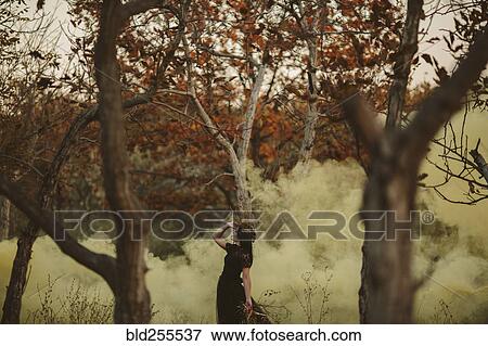 Stock Photo - Caucasian woman standing in fog in forest. Fotosearch