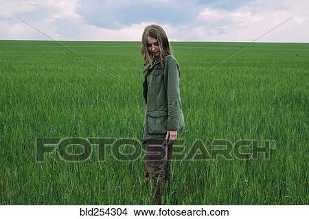 Picture - Caucasian woman standing in grass field. Fotosearch