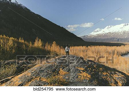 Stock Photography - Caucasian woman standing in rock near snowy mountain. Fotosearch