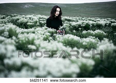 Stock Image - Caucasian woman standing in the field of wildflowers. Fotosearch