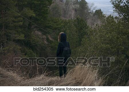 Stock Photography - Caucasian woman standing near trees carrying backpack. Fotosearch