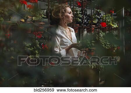 Stock Photo - Caucasian woman standing near wine bottles holding wine glass. Fotosearch