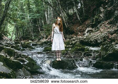 Stock Photo - Caucasian woman standing on rock in river. Fotosearch