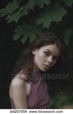 Picture - Caucasian woman standing under leaves. Fotosearch