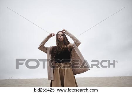 Stock Photography - Caucasian woman standing with arms raised at beach. Fotosearch