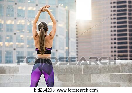 Stock Photography - Caucasian woman stretching arms on urban rooftop. Fotosearch
