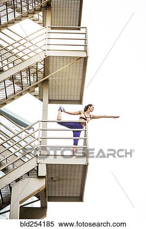 Stock Photography - Caucasian woman stretching leg on urban staircase. Fotosearch