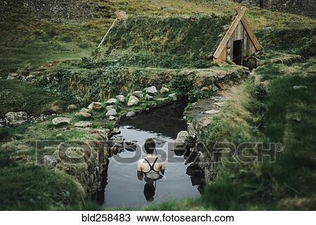 Stock Image - Caucasian woman swimming in pond near rural house. Fotosearch