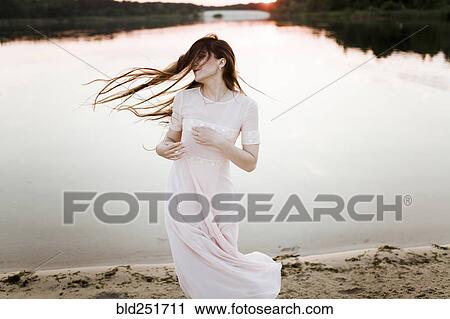 Stock Image - Caucasian woman tossing hair on beach. Fotosearch