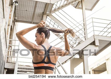 Picture - Caucasian woman tying hair in ponytail. Fotosearch