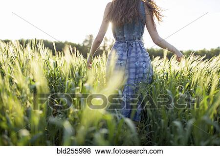 Caucasian woman walking in field of tall grass View Large Photo Image Stock Photo - Caucasian woman walking in field of tall grass. Fotosearch
