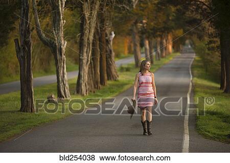 Stock Photo - Caucasian woman walking on path holding cowboy hat. Fotosearch