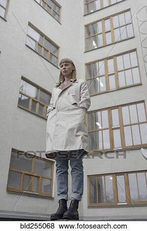 Stock Photo - Caucasian woman wearing a coat near building. Fotosearch