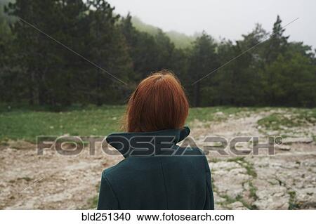 Stock Image - Caucasian woman wearing a coat with a collar in field. Fotosearch