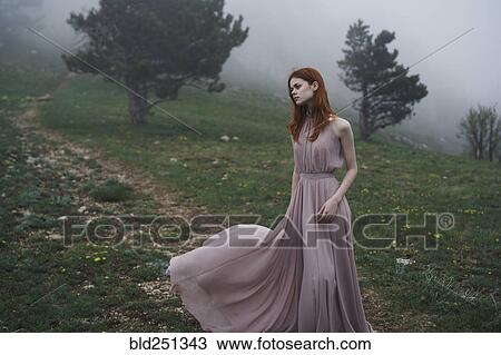 Stock Image - Caucasian woman wearing a dress in field. Fotosearch