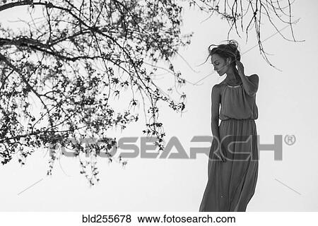 Caucasian woman wearing a dress near tree View Large Photo Image Stock Photo - Caucasian woman wearing a dress near tree. Fotosearch