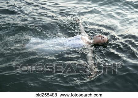 Caucasian woman wearing a dress floating in water View Large Photo Image Stock Photo - Caucasian woman wearing a dress floating in water. Fotosearch